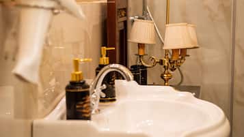 A bathroom with a white sink, gold faucets, and two wall-mounted lamps.