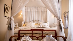 A neatly made bed with white linens, a bedside table with a lamp, and a canopy bed with white curtains. - Casa Isabella (Rocca San Giovanni)