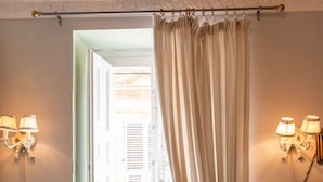 A room with a blue armchair, a table with a lamp, and a window with curtains. - Casa Isabella (Rocca San Giovanni)