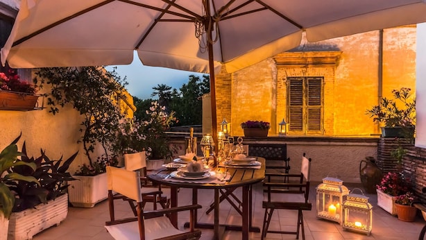 An outdoor dining area with a table set for two, surrounded by potted plants and lanterns. - Casa Isabella (Rocca San Giovanni)