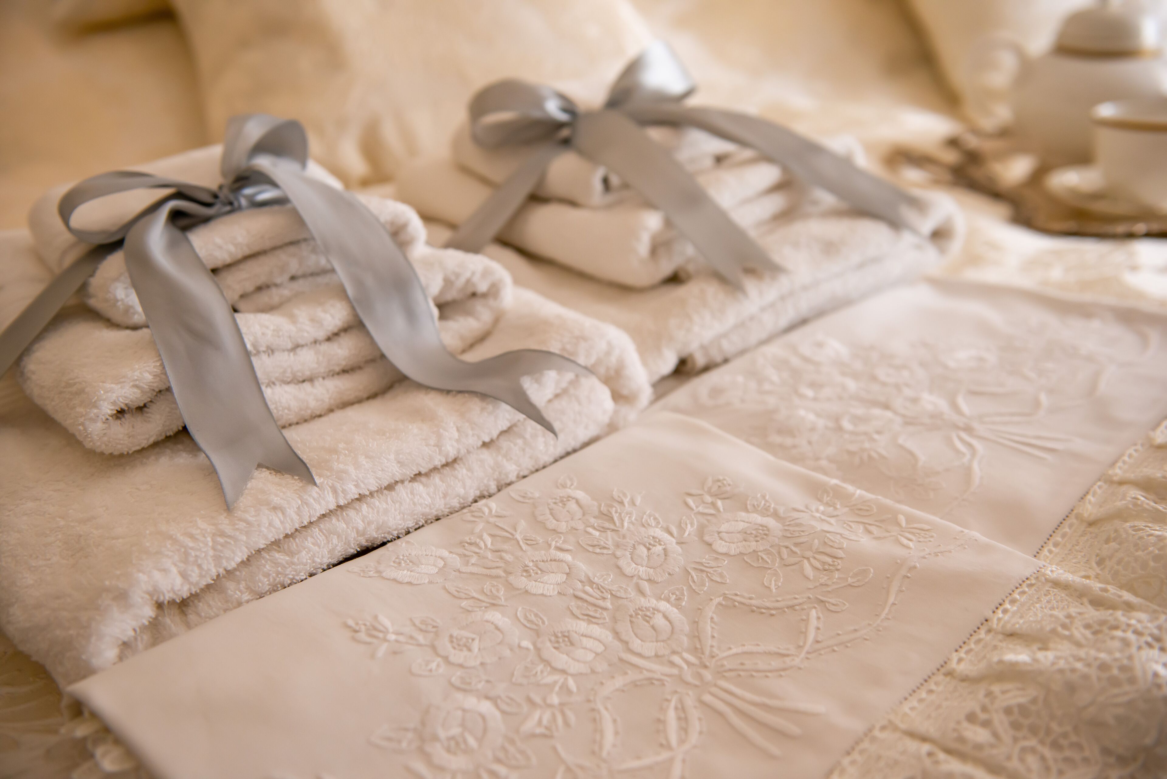 Toallas dobladas con cintas adornando una cama con un estampado floral bordado.