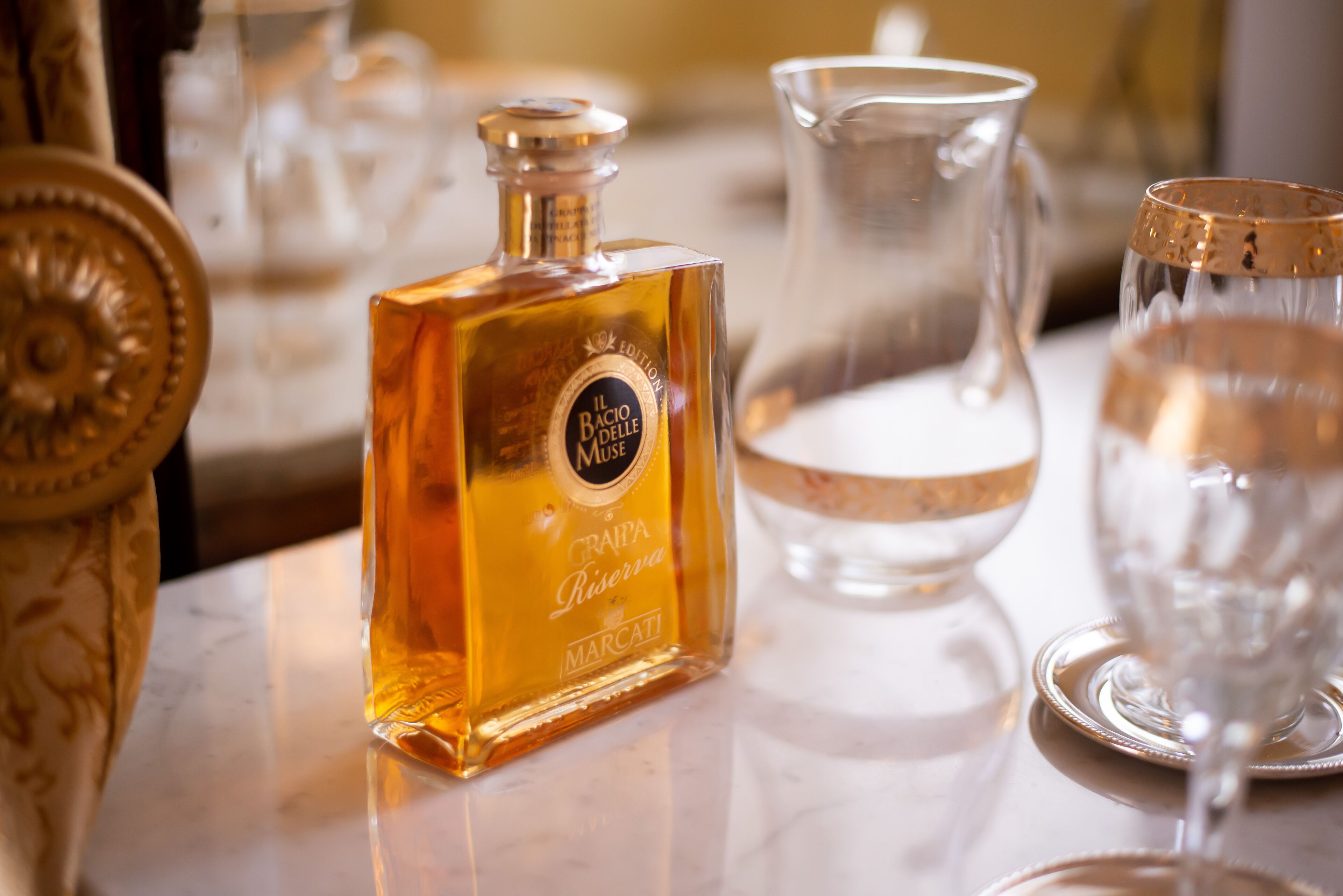 En flaske Il Bacio delle Rose vin, en kande og to glas på et marmorbord.