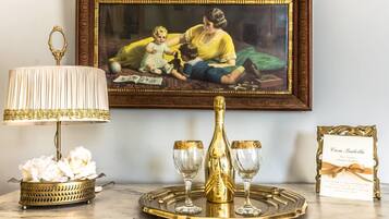 A table with a decorative lamp, a bottle, and two glasses on a tray, a framed photograph, and a card.