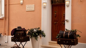 A building entrance with a wooden door, two wall-mounted light fixtures, and a sign above the door. - Casa Isabella (Rocca San Giovanni)