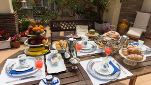 Mesa de desayuno al aire libre con diferentes alimentos, platos y un letrero que dice "Casa Isabella".