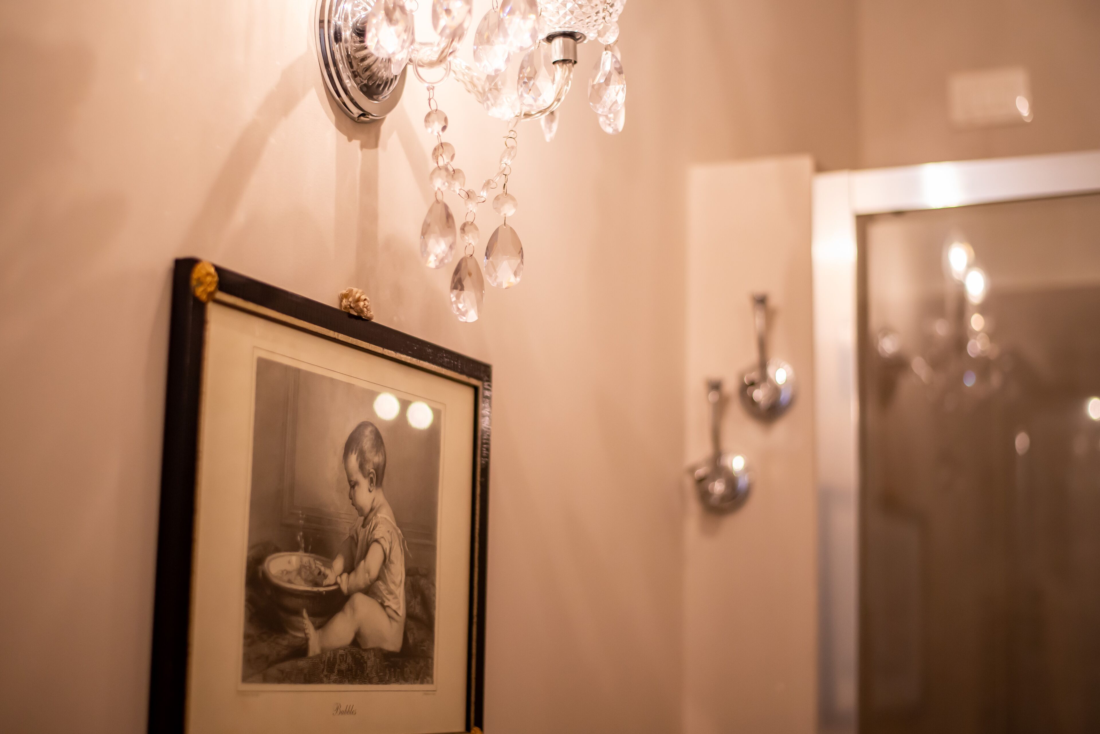 Fotografía blanco y negro en un marco sobre una pared, un candelabro y un espejo de baño.