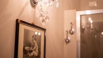 Fotografía blanco y negro en un marco sobre una pared, un candelabro y un espejo de baño.