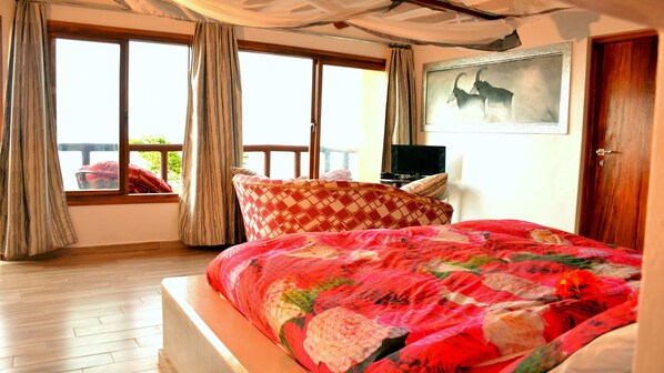 A bedroom with a large bed, a television, and a painting on the wall.