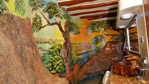 A bathroom with a mural of a tropical landscape, a wooden sink, and a mirror.