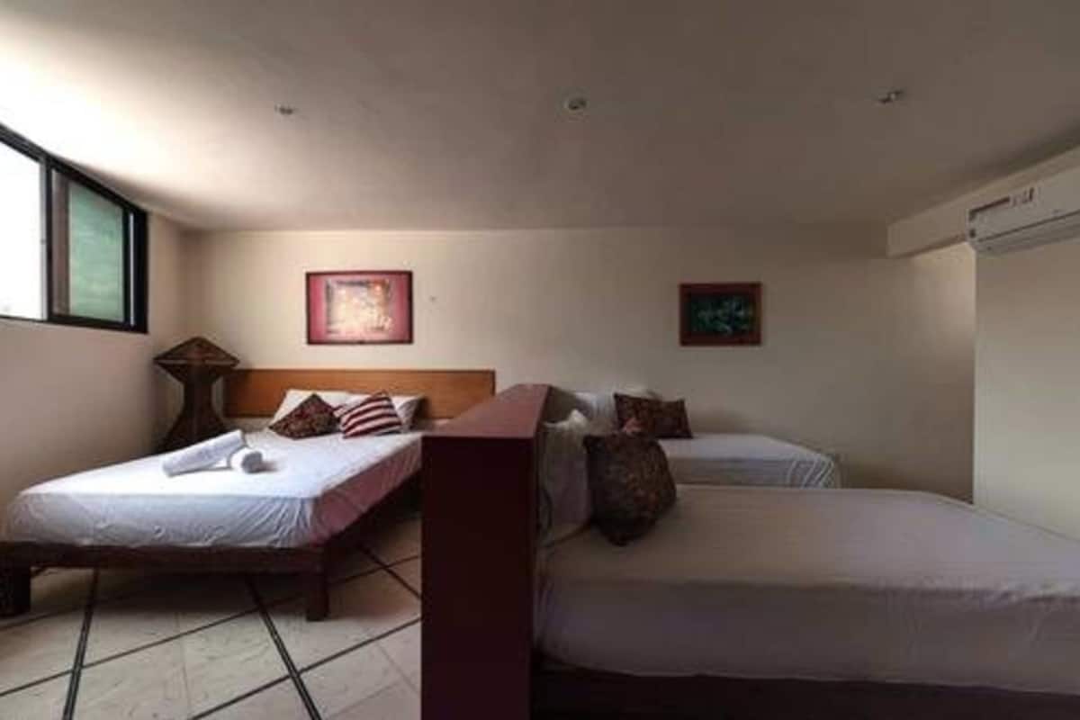 Una habitación con dos camas, una ventana y aire acondicionado instalado en la pared.