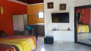 Un dormitorio con una cama, televisión, escritorio y una silla.