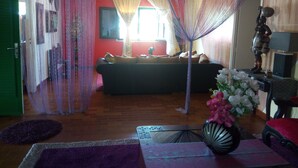 Una sala de estar con un sofá, un dosel decorativo, un jarrón con flores y un espejo.