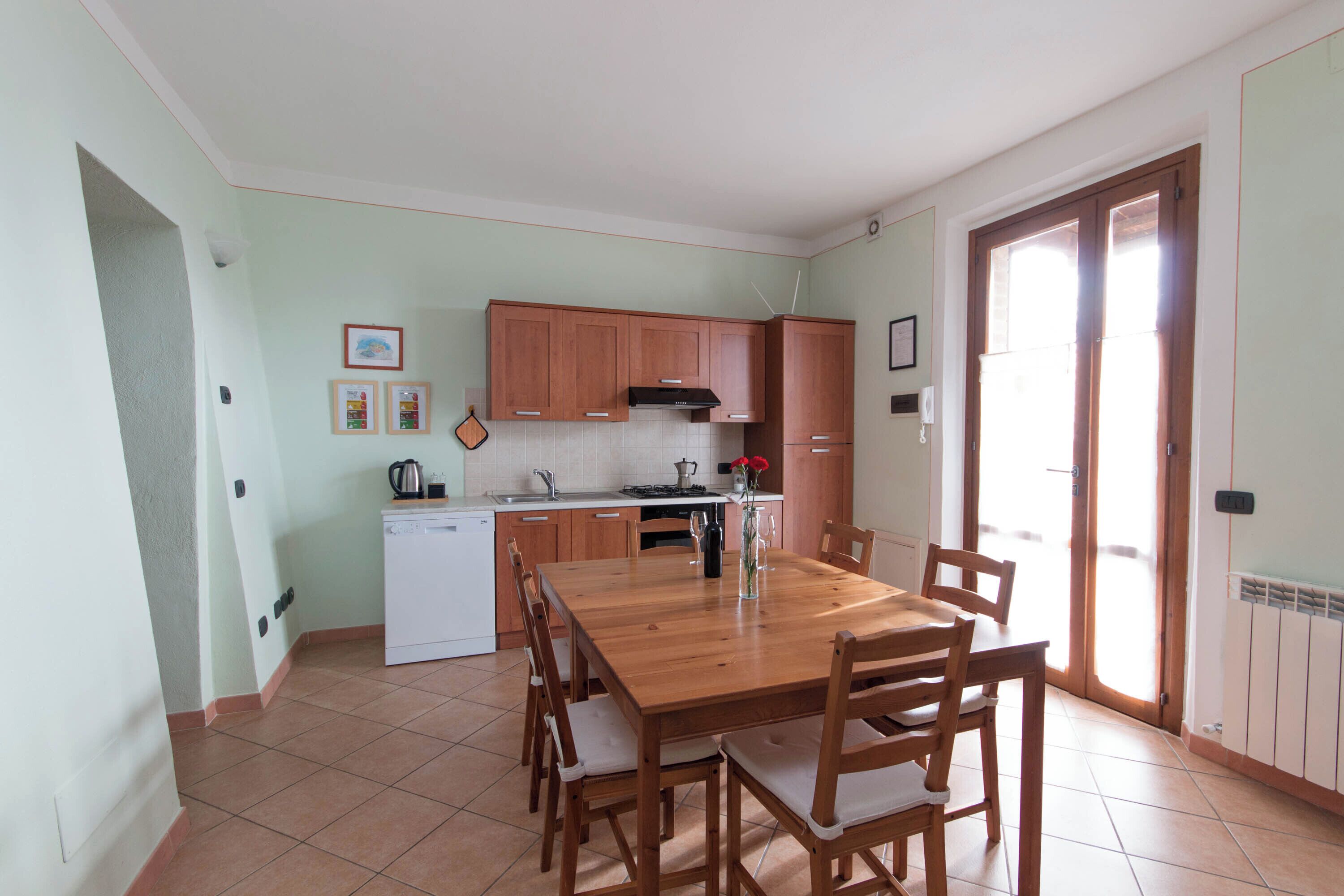 A kitchen with wooden cabinets, a white dishwasher, and a dining table with chairs.