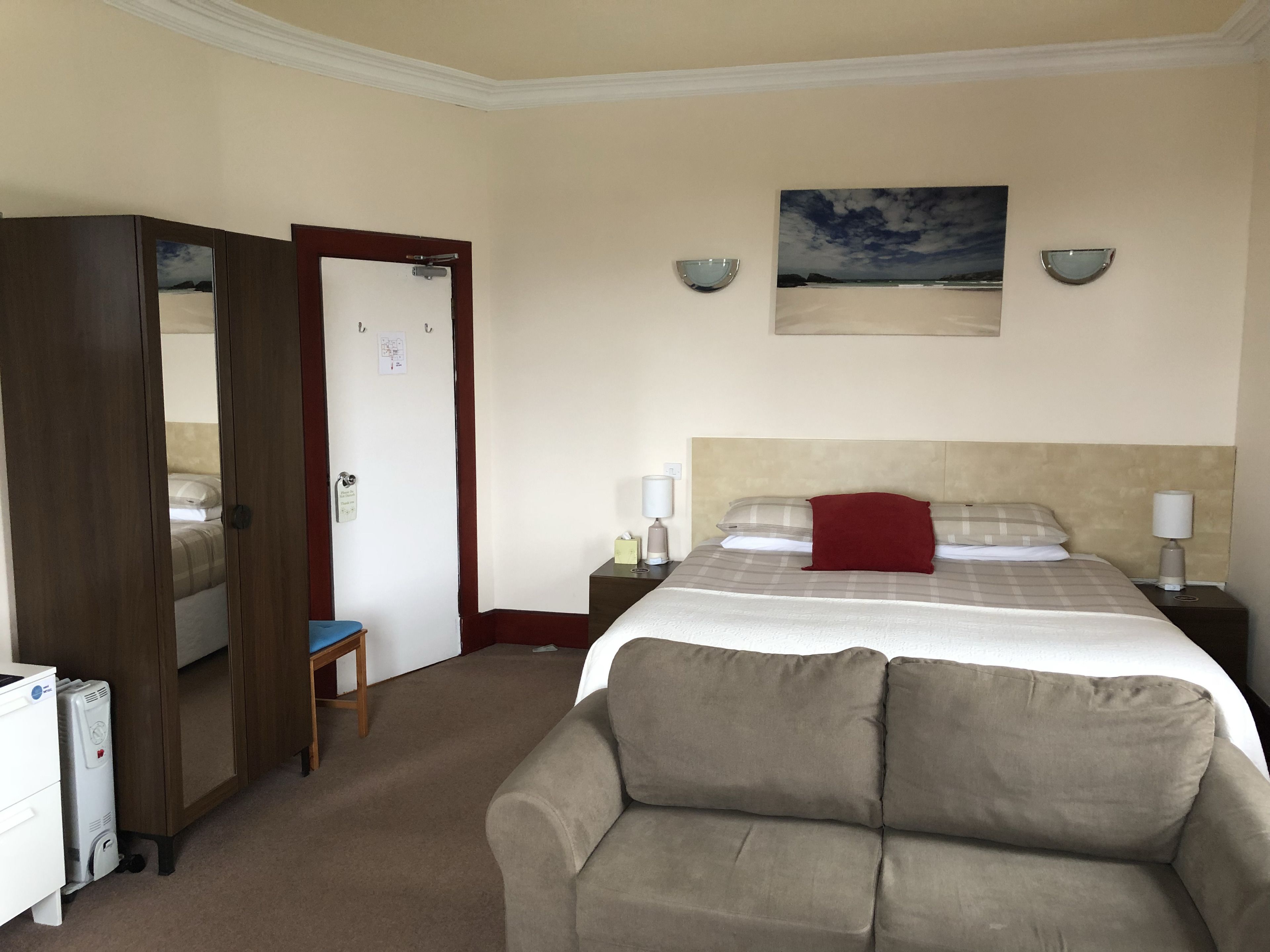 A hotel room with a bed, a sofa, a desk, and a wardrobe.