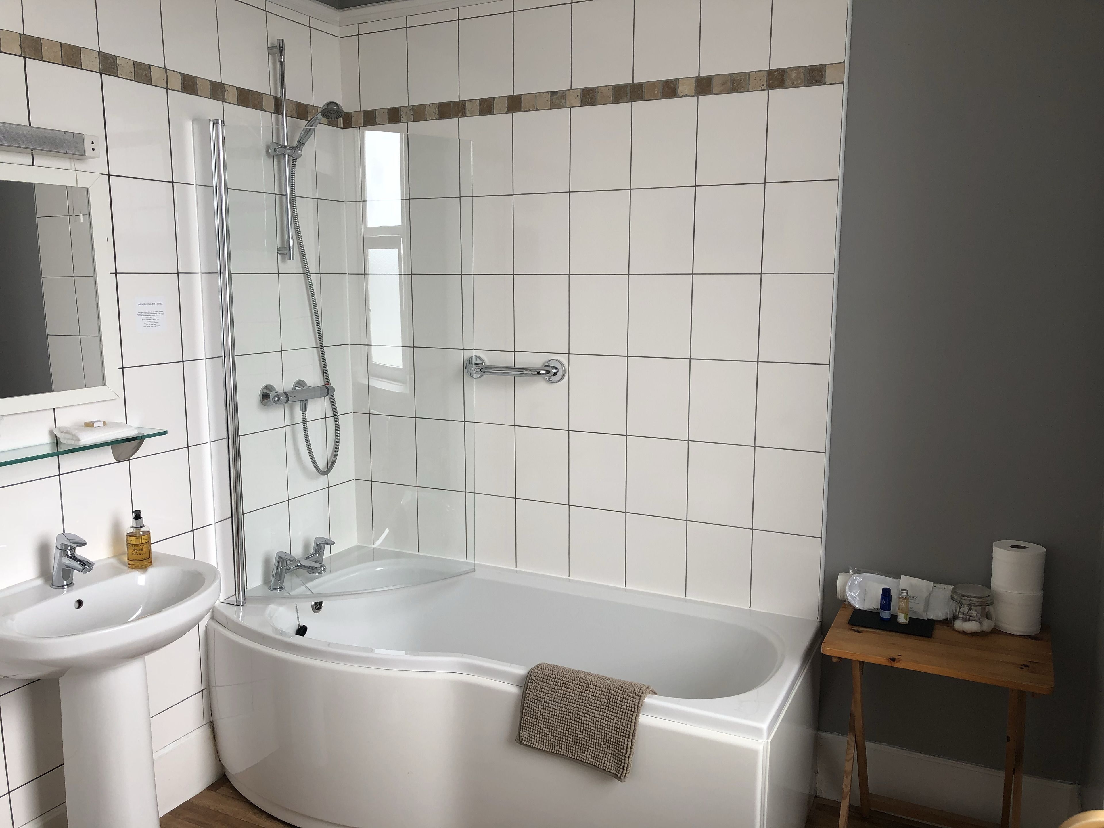 A modern bathroom with a bathtub, a glass-enclosed shower, a sink, and a mirror.