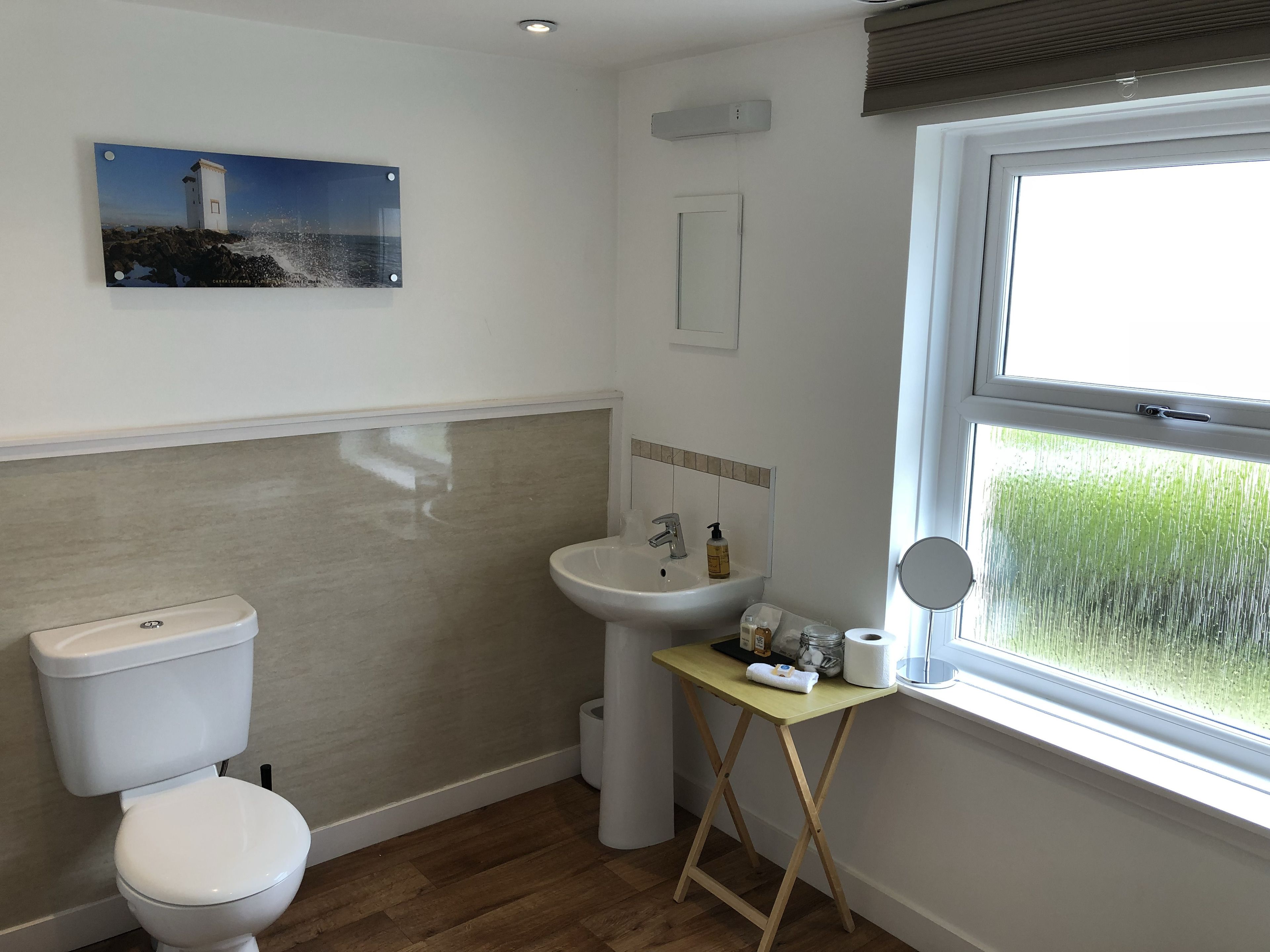 A bathroom with a toilet, sink, and window.