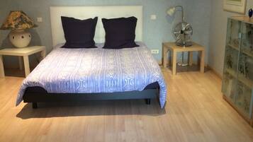 A bedroom with a bed, two nightstands, a floor lamp, and wall art.
