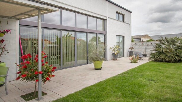 A modern house with a patio, large sliding glass doors, and a well-maintained lawn. - Loft Zen Bordeaux (Bordeaux)