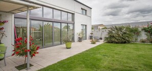 A modern house with a patio, large sliding glass doors, and a well-maintained lawn. - Loft Zen Bordeaux (Bordeaux)