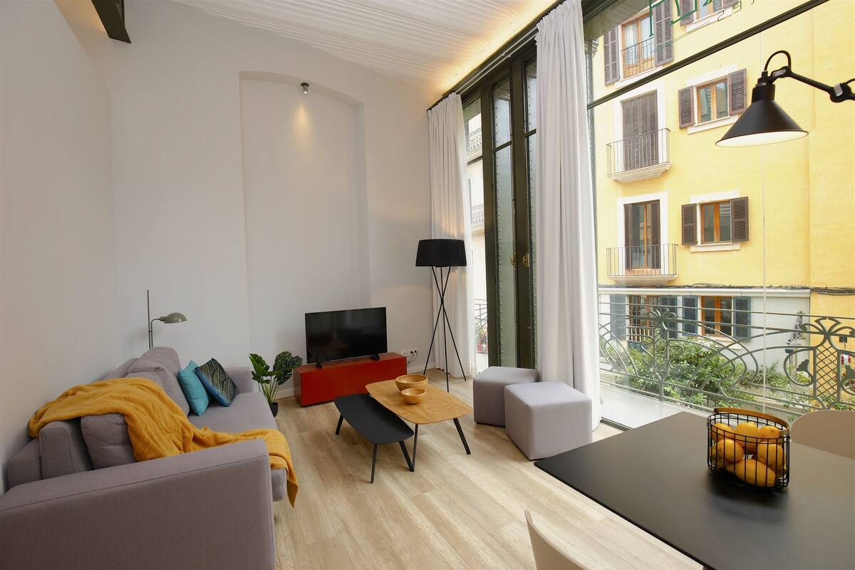 Ein modernes Wohnzimmer mit Sofa, Couchtisch, Fernseher und Essbereich.