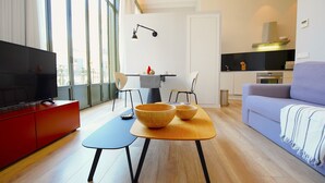 A modern living room with a flat-screen TV, a dining table with a bowl, and a sofa. - L'Aguila Apartments Turismo de Interior  (Palma de Mallorca)