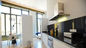 A modern kitchen with a black countertop, stainless steel appliances, and a view through large windows. - L'Aguila Apartments Turismo de Interior  (Palma de Mallorca)