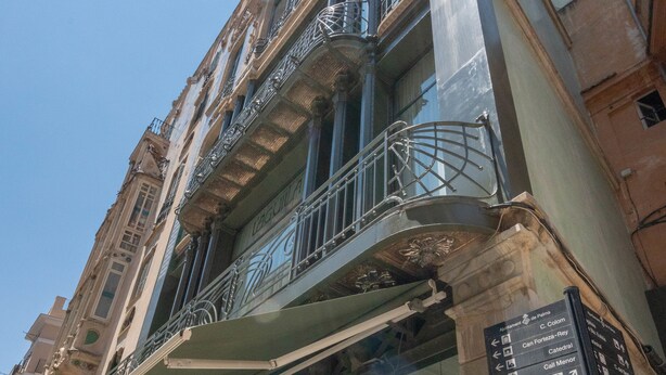 A multi-story building with balconies and a sign indicating directions to various locations. - L'Aguila Apartments Turismo de Interior  (Palma de Mallorca)