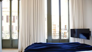 A hotel room with a bed, a TV, and a balcony with curtains. - L'Aguila Apartments Turismo de Interior  (Palma de Mallorca)