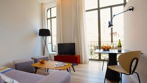 A modern living room with a sofa, a coffee table, a TV, and a dining area with a table and chairs. - L'Aguila Apartments Turismo de Interior  (Palma de Mallorca)