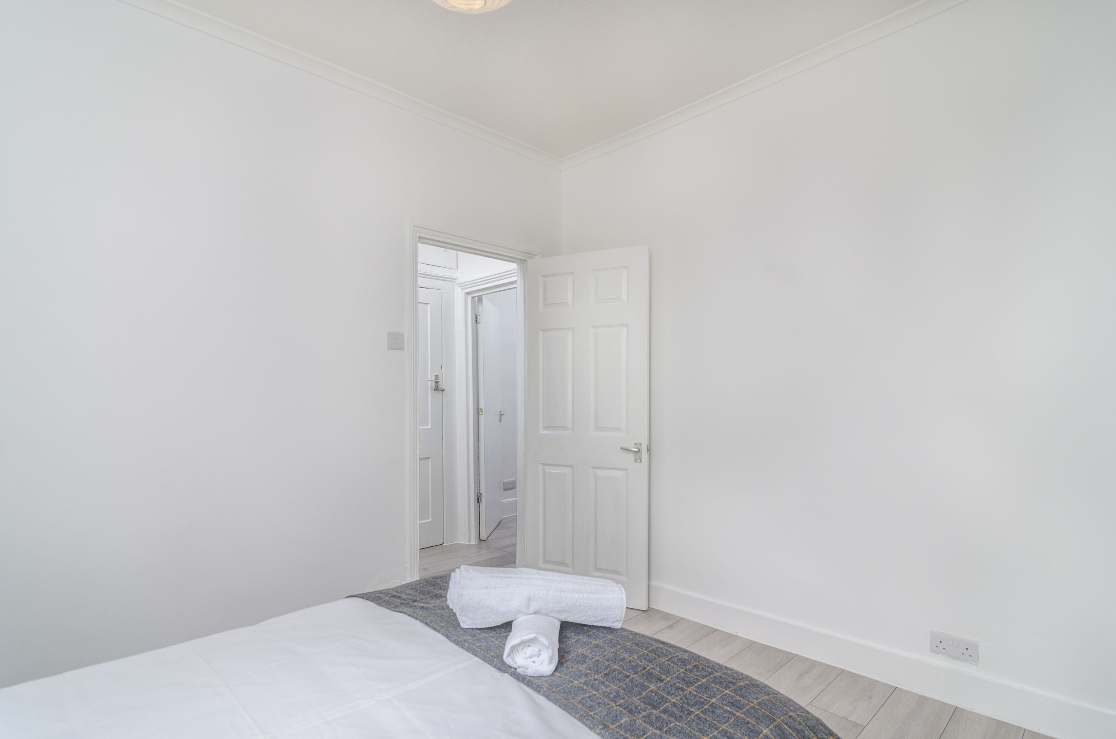Una camera d'albergo con un letto, una porta e un piccolo tappeto.
