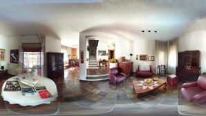 Amplia sala de estar con una gran mesa redonda, sofás de cuero y una escalera que conduce a otra habitación.