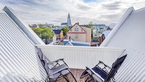 A view from a balcony with metal railings, overlooking a town with various buildings, including a church with a tall spire. - Iðunn Apartments by Heimaleiga (Reykjavik)