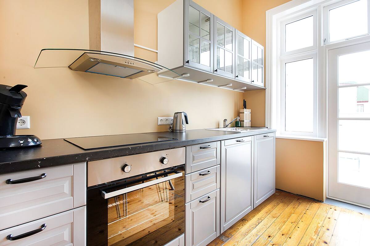 A kitchen with a stove, oven, cabinets, and a window.