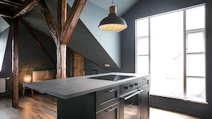 A modern kitchen with a large island, wooden beams, and a large window. - Iðunn Apartments by Heimaleiga (Reykjavik)