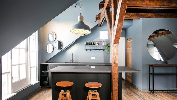A modern kitchen with a central island, two stools, a hanging light fixture, and a large window. - Iðunn Apartments by Heimaleiga (Reykjavik)