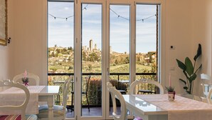 A dining area with a view of a cityscape through large glass doors. - B & B La Cornice - Gina Room With Bathroom and Private Terrace (San Gimignano)
