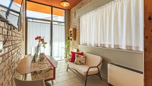 A cozy living room with a brick wall, a sofa, a dining table, and a radiator. - B & B La Cornice - Gina Room With Bathroom and Private Terrace (San Gimignano)