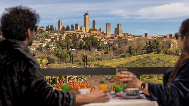 A couple dining at a table with a view of a historic cityscape. - B & B La Cornice - Gina Room With Bathroom and Private Terrace (San Gimignano)