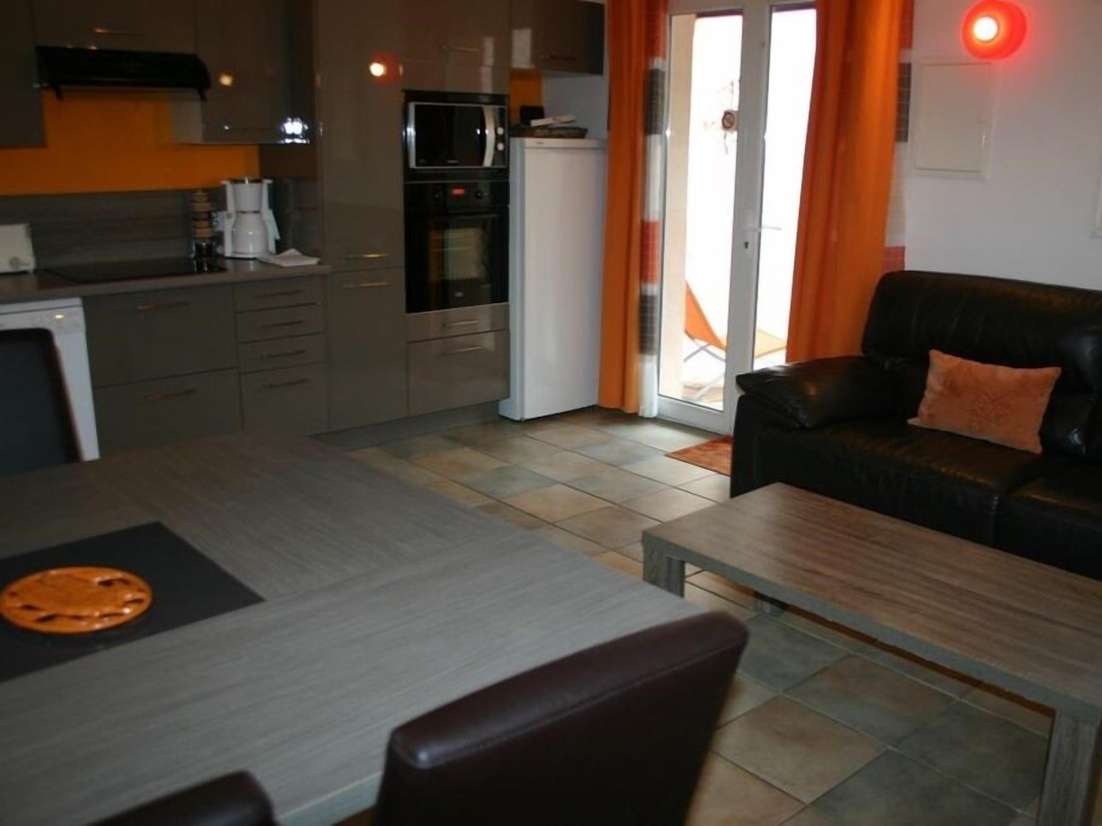 Un espace de vie compact comprenant un coin cuisine, un coin repas et un espace détente avec un canapé et une table basse.