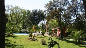 Um jardim bem cuidado com piscina, palmeiras e um gazebo.
