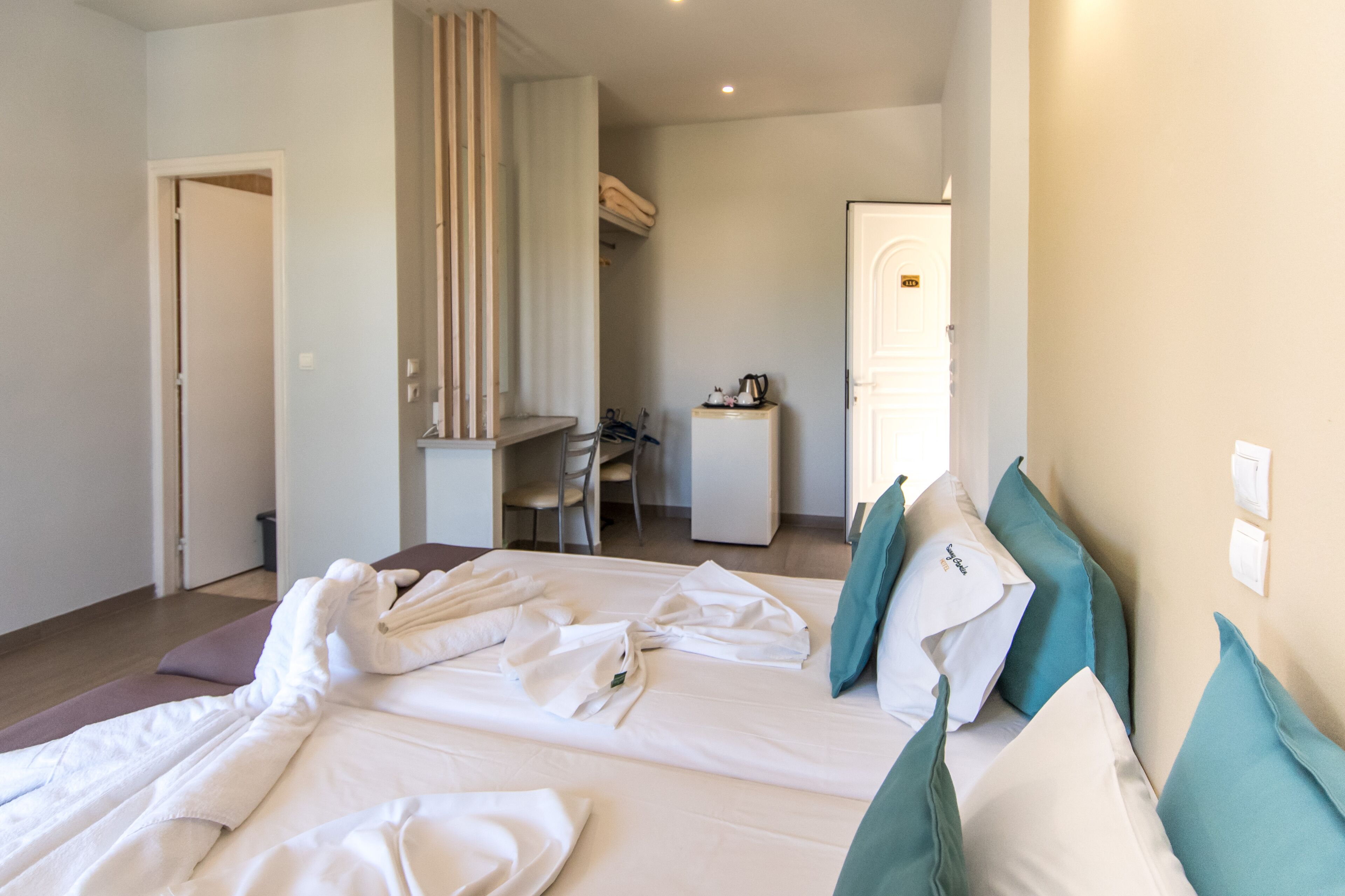 A hotel room with a neatly made bed, a desk, and a chair.