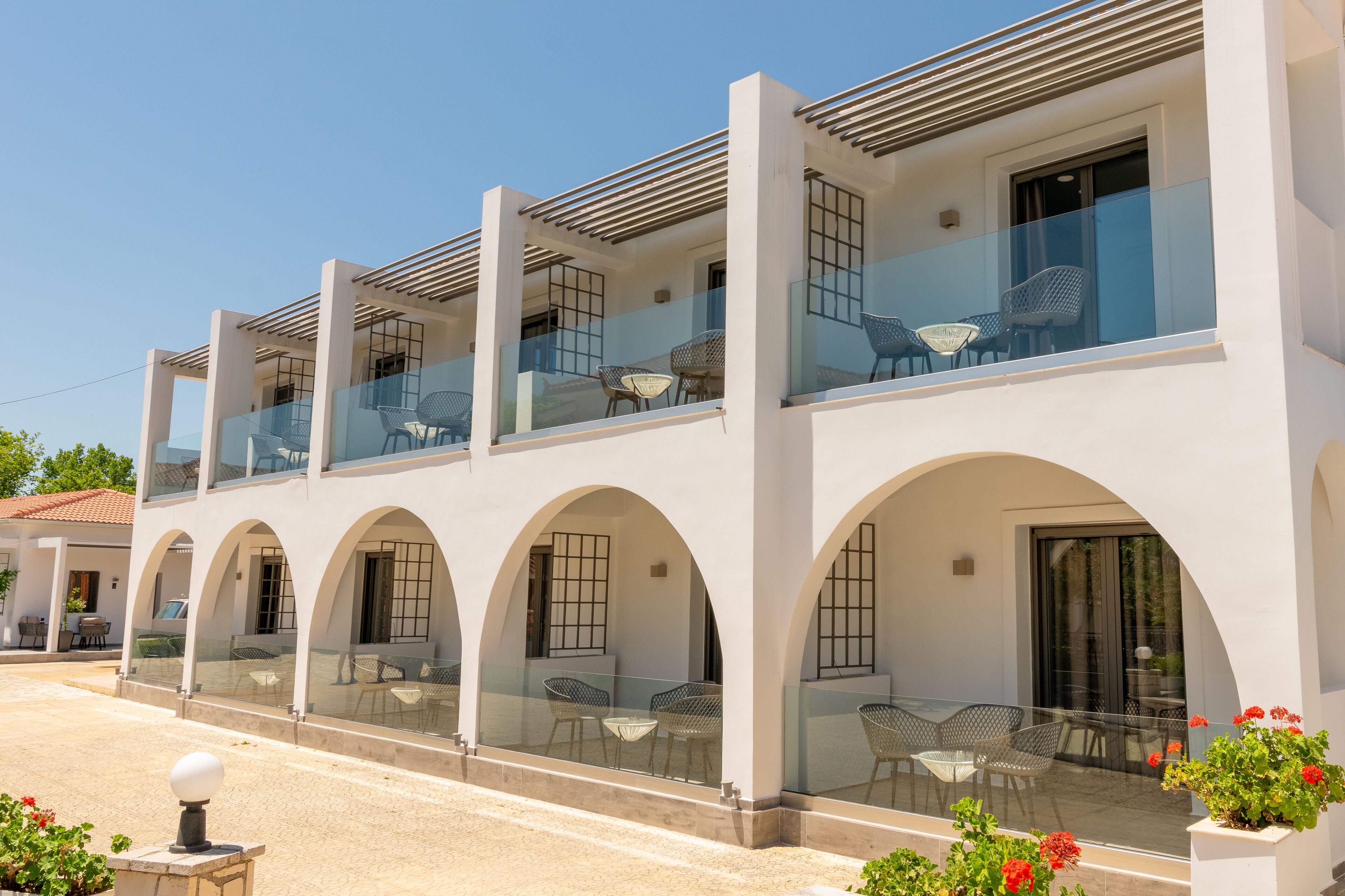 A modern building with multiple balconies, each with glass railings and outdoor seating.