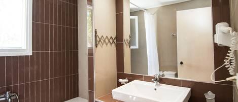 Une salle de bain moderne avec une baignoire, un grand miroir et un sèche-cheveux.