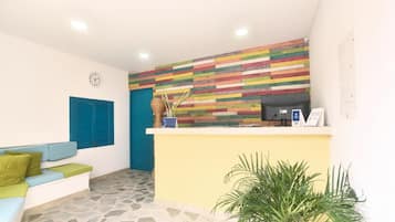 Un área de recepción con una pared de madera colorida, un mostrador de recepción, un reloj y una planta.