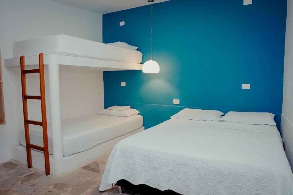 Habitación con literas, una escalera, una lámpara colgante y una pared azul de acento.