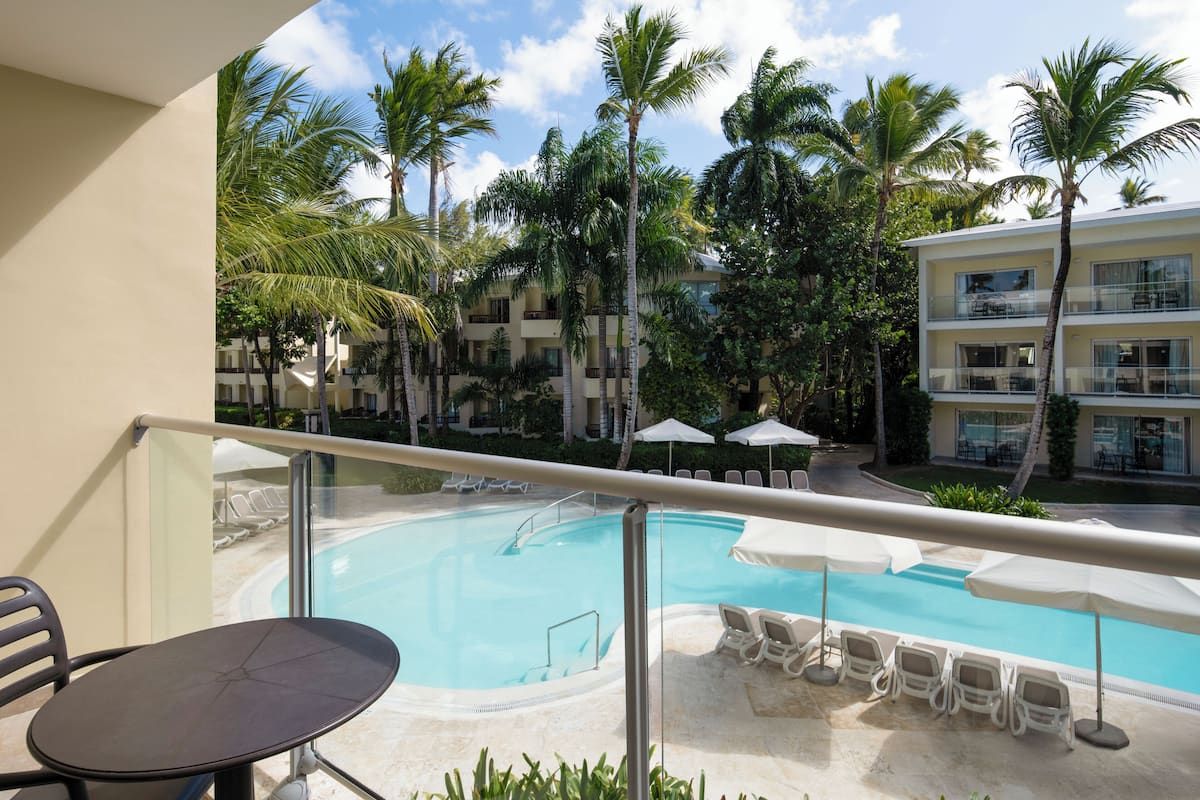 Un balcon avec une piscine, des chaises longues et des palmiers.