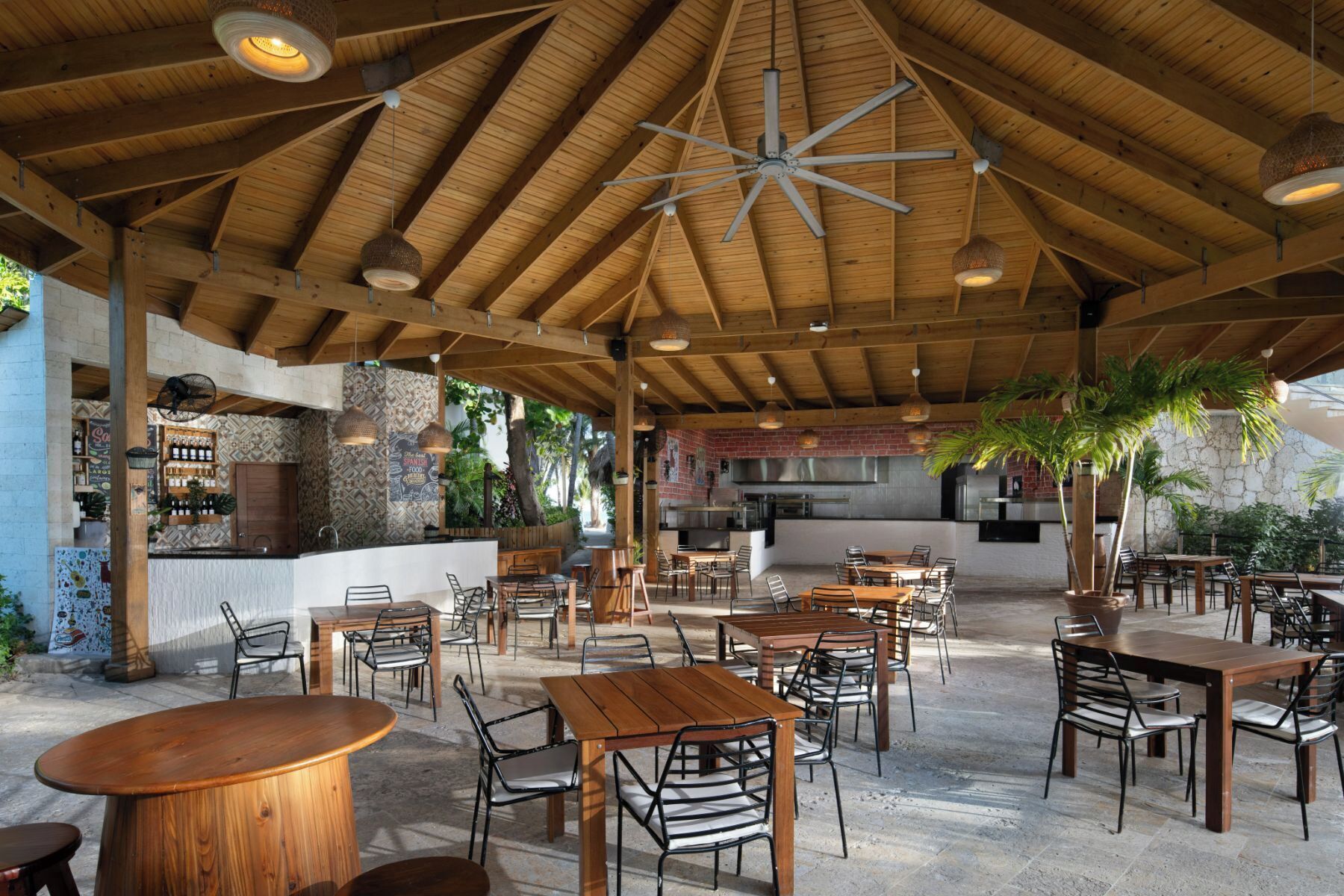 Un espace de restauration en plein air avec des tables et des chaises en bois, un bar et un coin cuisine.