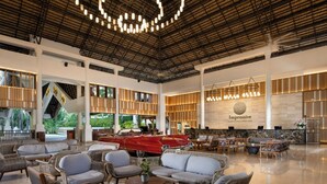 Eine großzügige Lobby mit Korbmöbeln, einem roten Cabrio und einem großen Schild für 'Impressive Resorts & Spas - Punta Cana'.