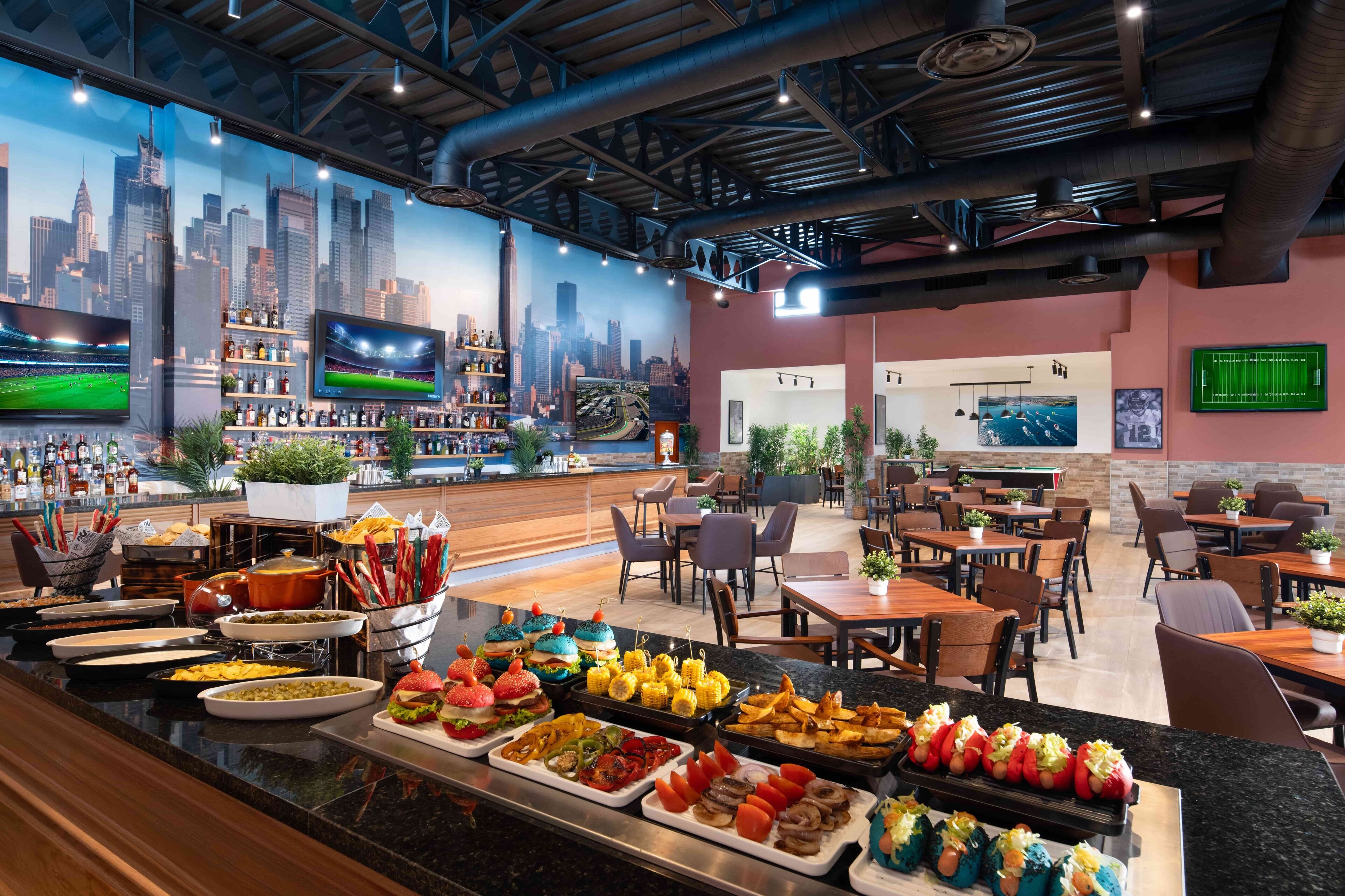 Restaurante com um mural da paisagem urbana, área de bar e diversos pontos de comida.
