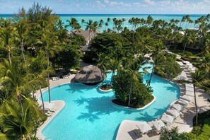 Una piscina de resort en un entorno tropical, rodeada de palmeras y vistas al océano.